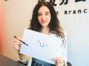 الشابة المصرية أسماء مصطفى إبراهيم وهي تظهر كلمة "قلب" مكتوبة بالفرشاة.